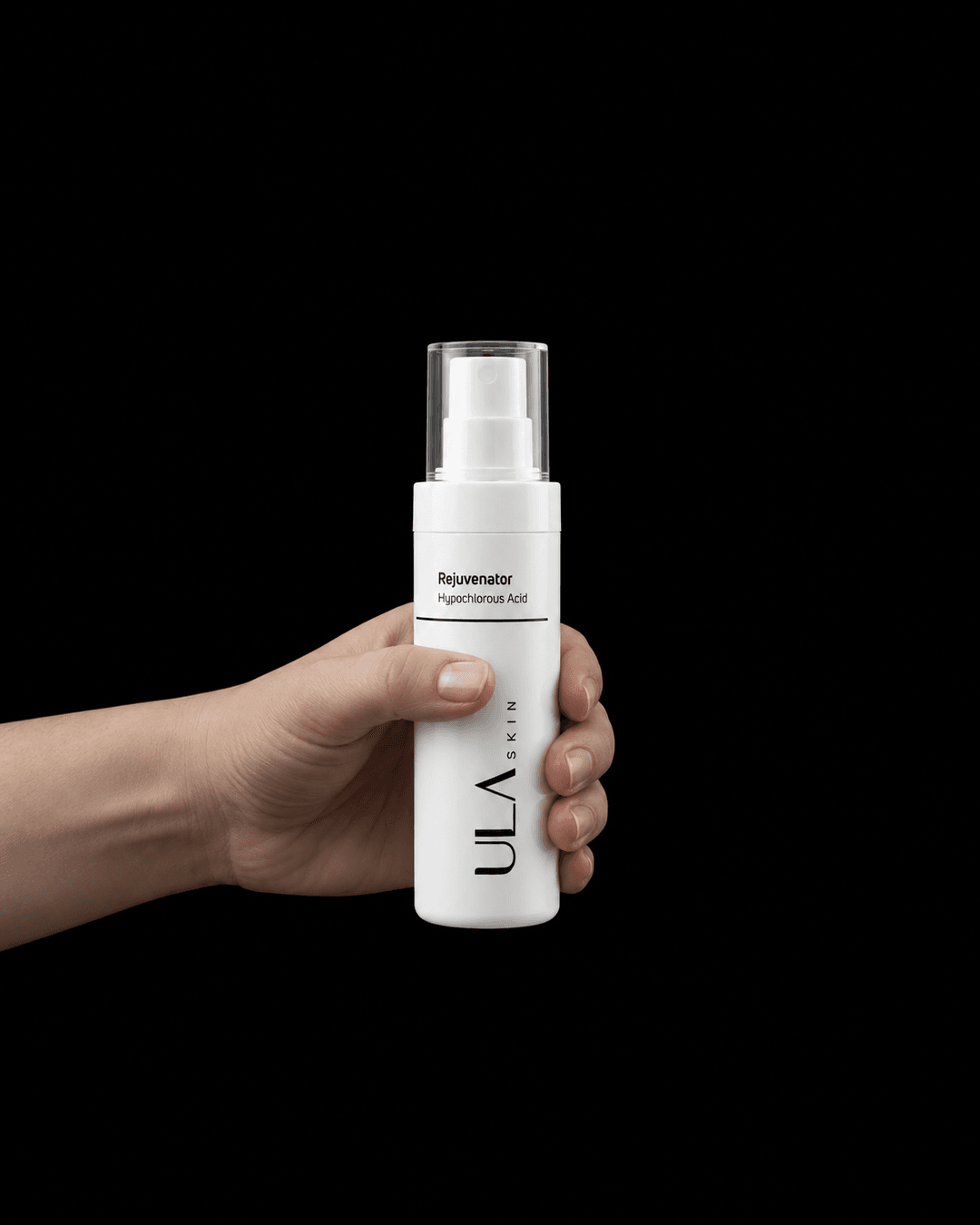 A hand holding a white ULA Skin Rejuvenator spray bottle against a black background, with no text or graphics added.