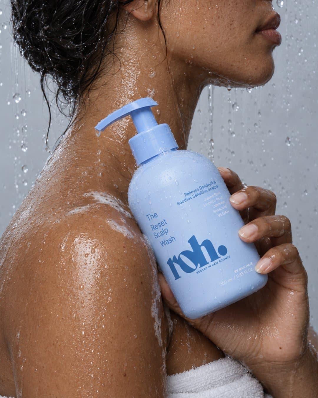 Model in the shower holding a periwinkle ROH pump bottle against her shoulder