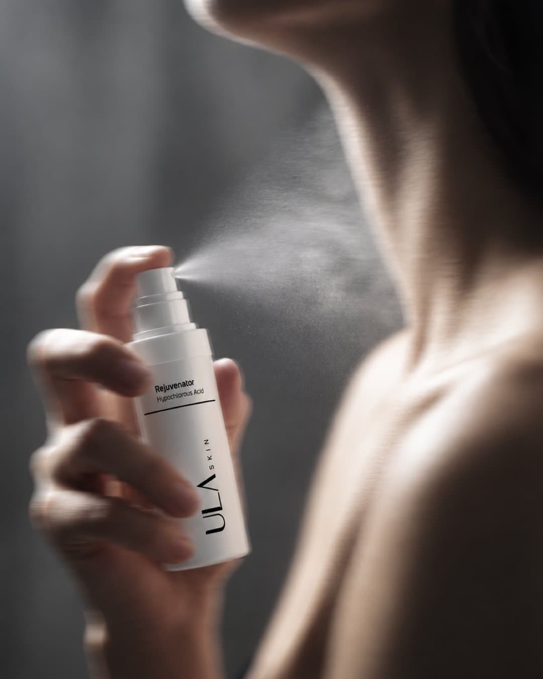 Hand spraying a mist onto the neck and collarbone