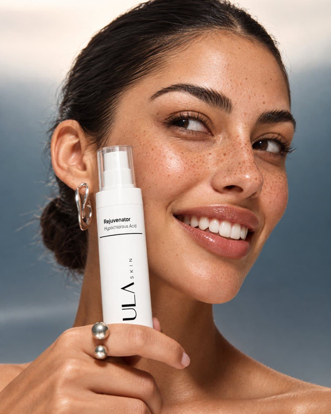 Smiling model holding a ULA spray bottle at her cheek