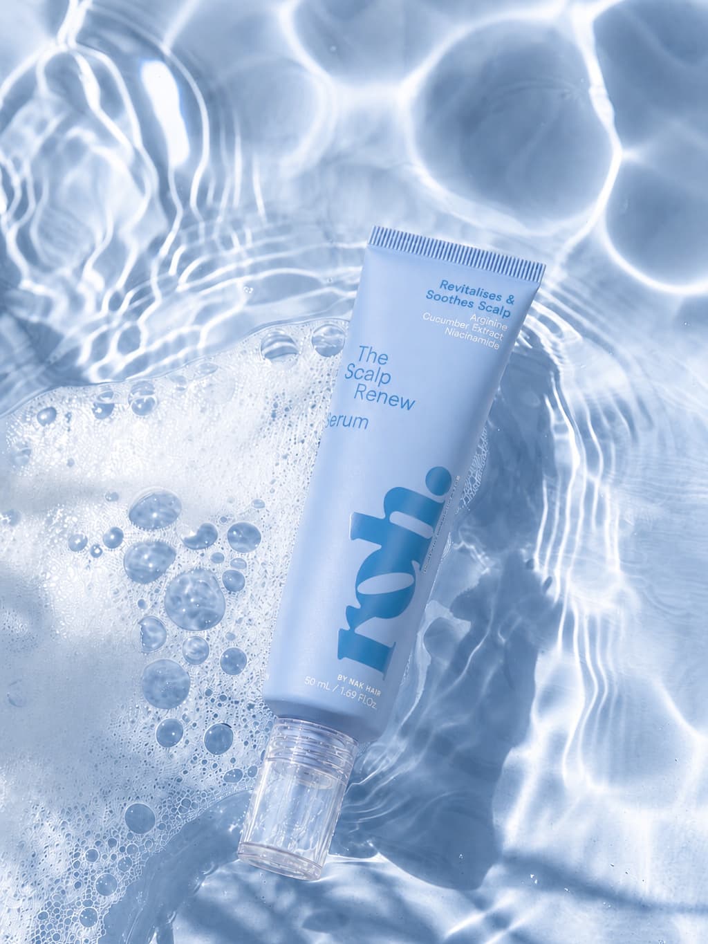 Scalp renew serum tube floating in rippling water, periwinkle packaging lit from below
